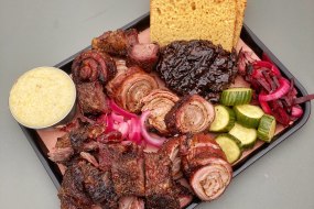 A tray of rolled lamb breast, beef short ribs, bbq glazed hen of the woods mushroom, cheese grits, pickles, and beef tallow brioche.