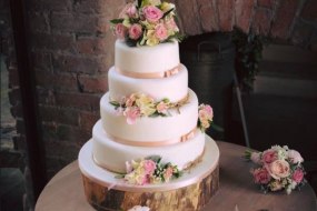 A Beautiful Four Tier weddig cake in a simple blush pink theme, decorated with fresh flowers, by The Daisy Chain Bakery