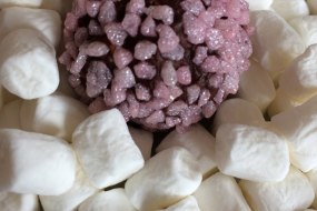 Champagne truffle coated in strawberry sugar on a bed of mini marshmallows