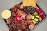 A tray of rolled lamb breast, beef short ribs, bbq glazed hen of the woods mushroom, cheese grits, pickles, and beef tallow brioche.