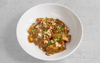 Homemade plin ravioli filled with artichoke in black garlic cream, hazelnuts