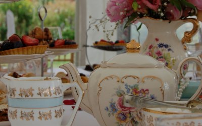 An afternoon tea with beautiful vintage china, table decorations and chair sashes.