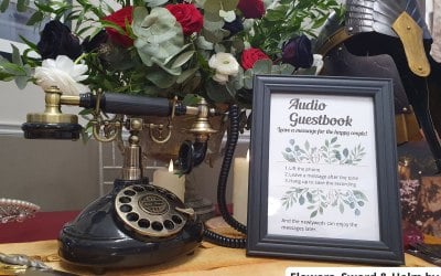 A black vintage audio guestbook phone and frame set up with flowers. 