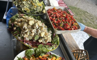 Salad bar with barbecue burgers and chicken skewers . 