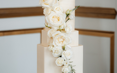 Traditional style 4 tier wedding cake featuring hexagon terms and fresh roses - Gosfield Hall